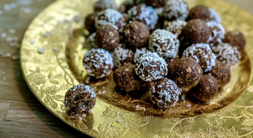 Chokladbollar med **harina de avena** (havregryn) på ett gyllene fat. En är uppäten.