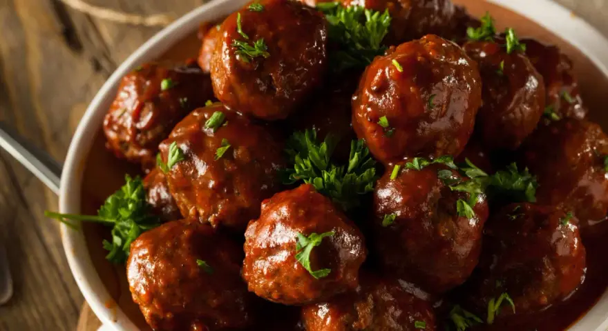 En skål med saftiga köttbullar i en rik, mörk sås, toppade med färsk persilja. Dessa albondigas de carne con salsa ser otroligt goda ut!