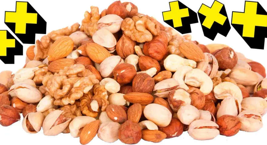 En hög med nötter, som mandlar, valnötter och pistagenötter, med gula kors i bakgrunden. Perfekt för en energiboost!