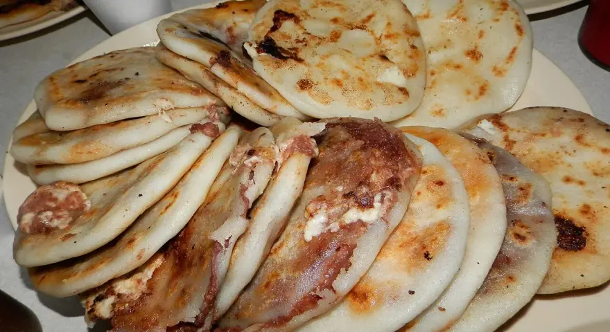 En tallrik med staplade pupusas salvadoreñas, gyllene och fyllda med läckra ingredienser.