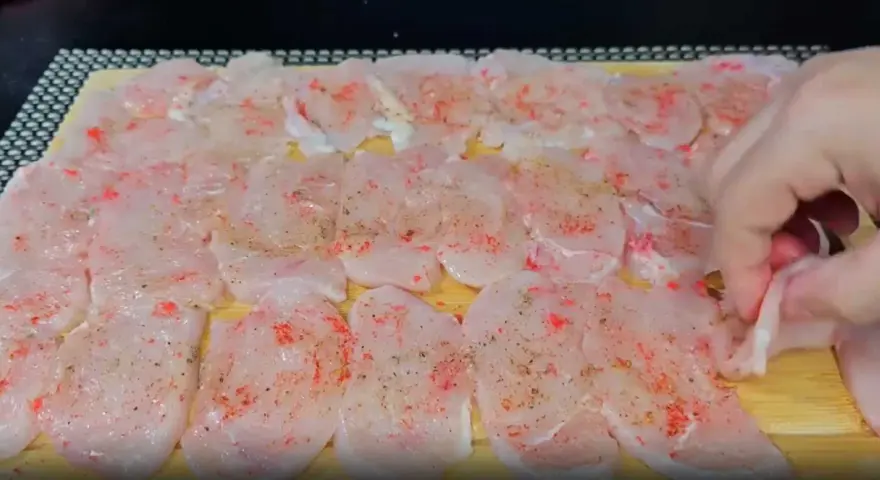 Tunna skivor av kyckling, kryddade med paprika och peppar, ligger redo att bli till saftiga medallones de pollo.