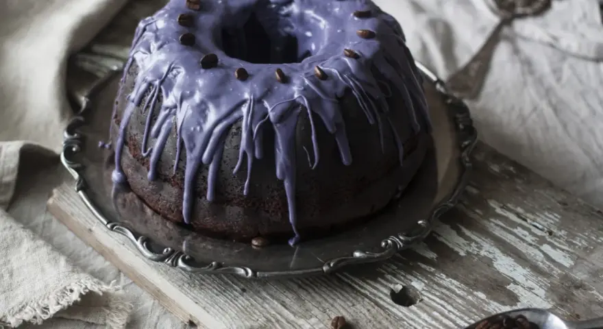 Mörk chokladkaka med lila glasyr och kaffebönor, ett härligt pastel de cafe.