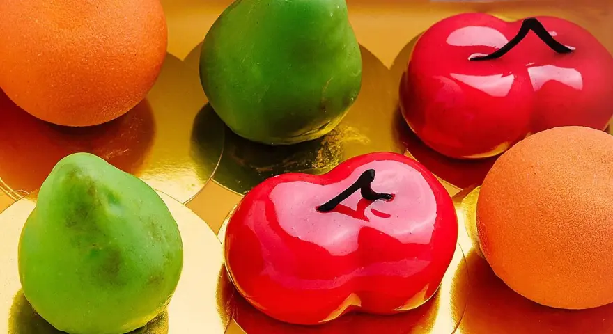 Sju glaserade bakverk i form av frukter: päron, körsbär och apelsiner. Dessa pasteles de frutas ser utsökta ut!