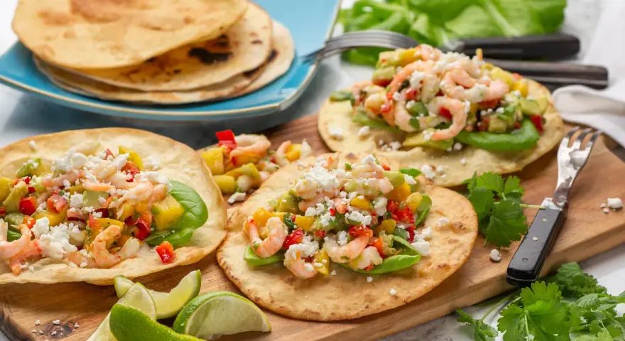 Tre läckra tostadas de camarón med räkor, avokado och mango. Serveras med limeklyftor och färsk koriander.