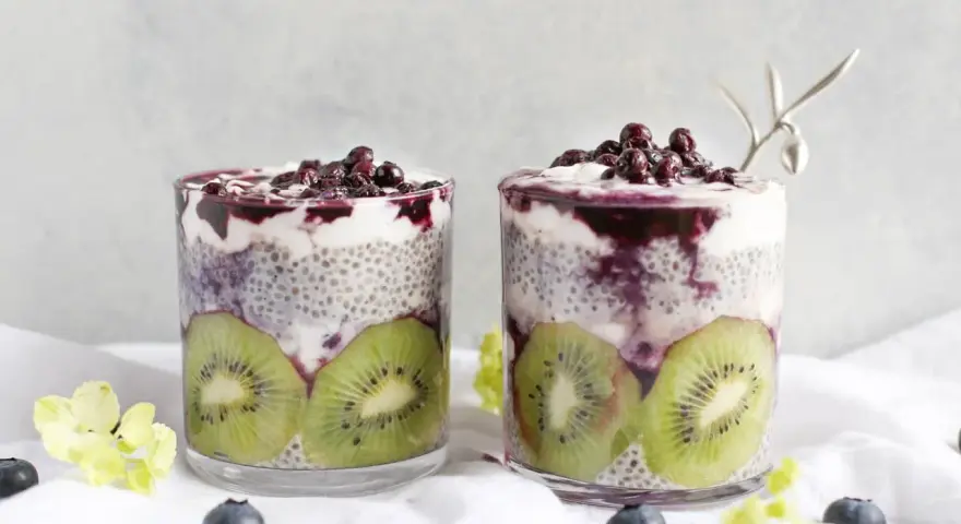 Två glas med chiapudding, kiwi och blåbär. En hälsosam frukost med nyttiga semillas de chia.