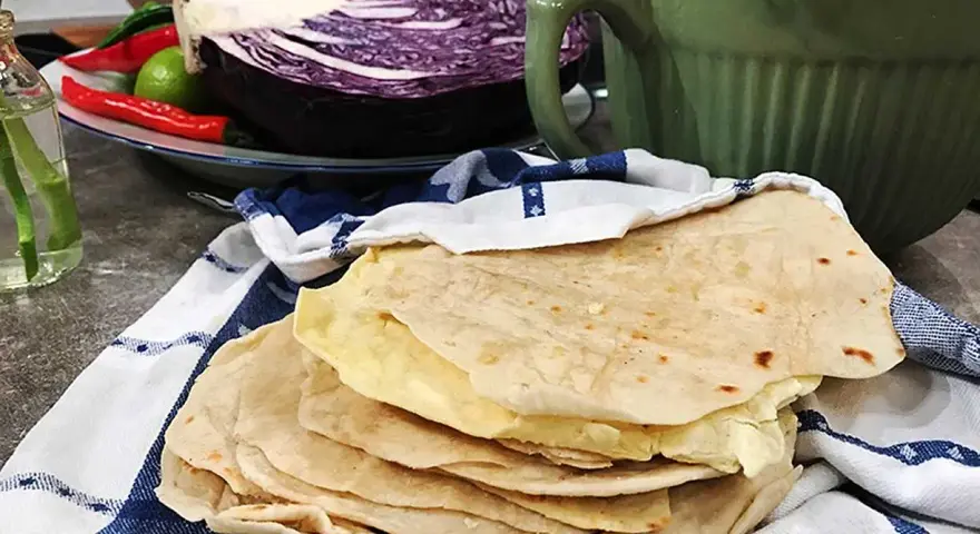 Färska tortillas de harina, redo att fyllas med goda ingredienser. I bakgrunden syns rödkål, chili och koriander.