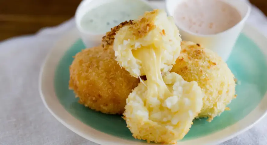 Krispiga papas rellenas de queso med smält ost som rinner ut. Serveras med två dippsåser.