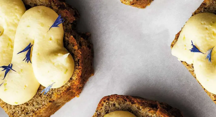 Skivor av saftig sockerkaka med fluffig citronkräm och blå blomblad. Perfekt för en fika, tack vare bakpulver som ger den luftiga konsistensen.