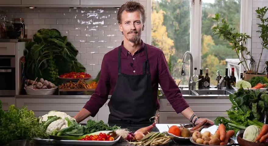 En kock i köket med ett överflöd av färska grönsaker, redo att visa olika tipos de cortes de vegetales.