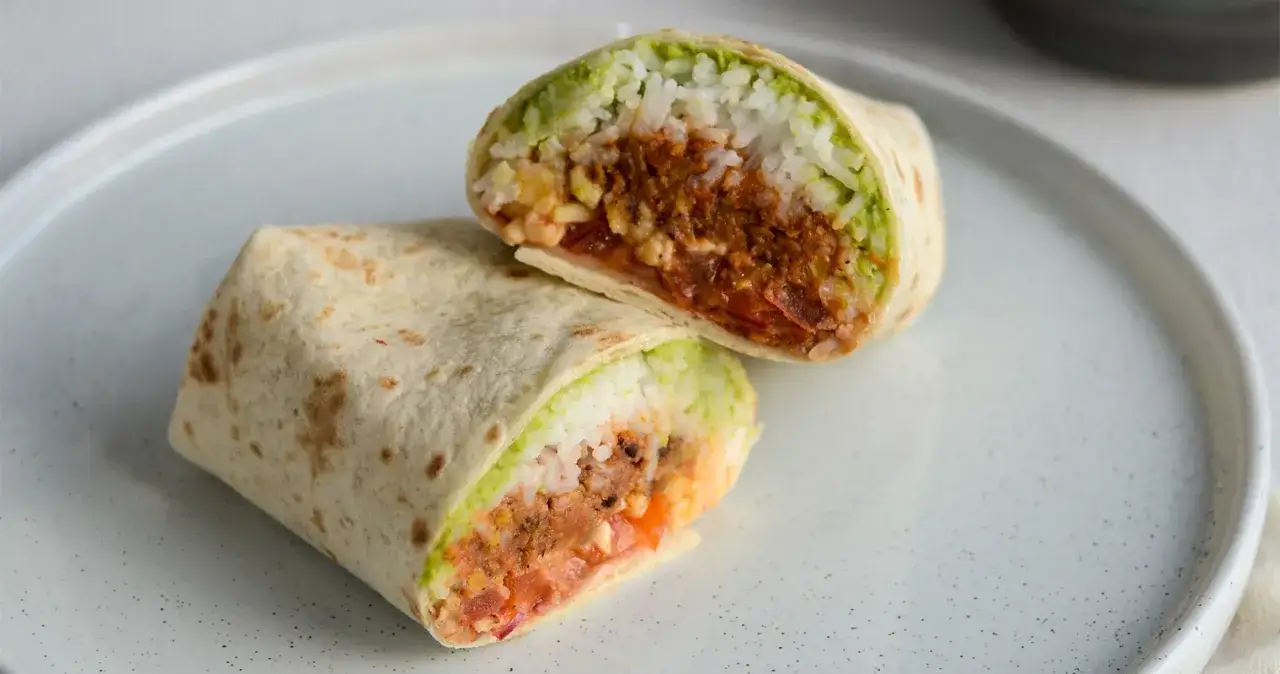En skuren burrito med ris, guacamole och kryddig köttfärs. Perfekt för att lära sig como hacer burritos de res.