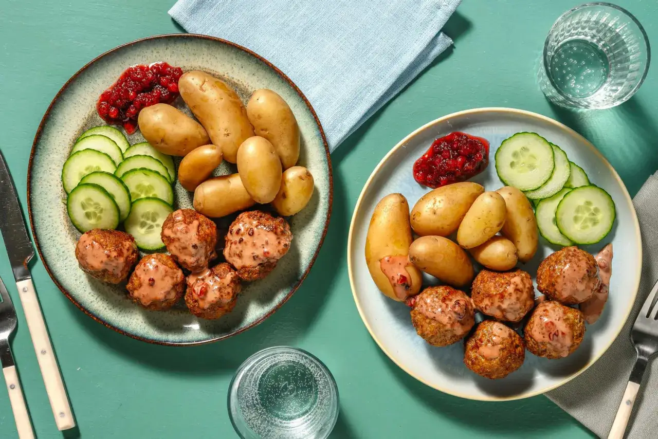 Tv&aring; tallrikar med k&ouml;ttbullar, potatis, gurka och lingonsylt. Perfekt f&ouml;r hemmagjorda recept.