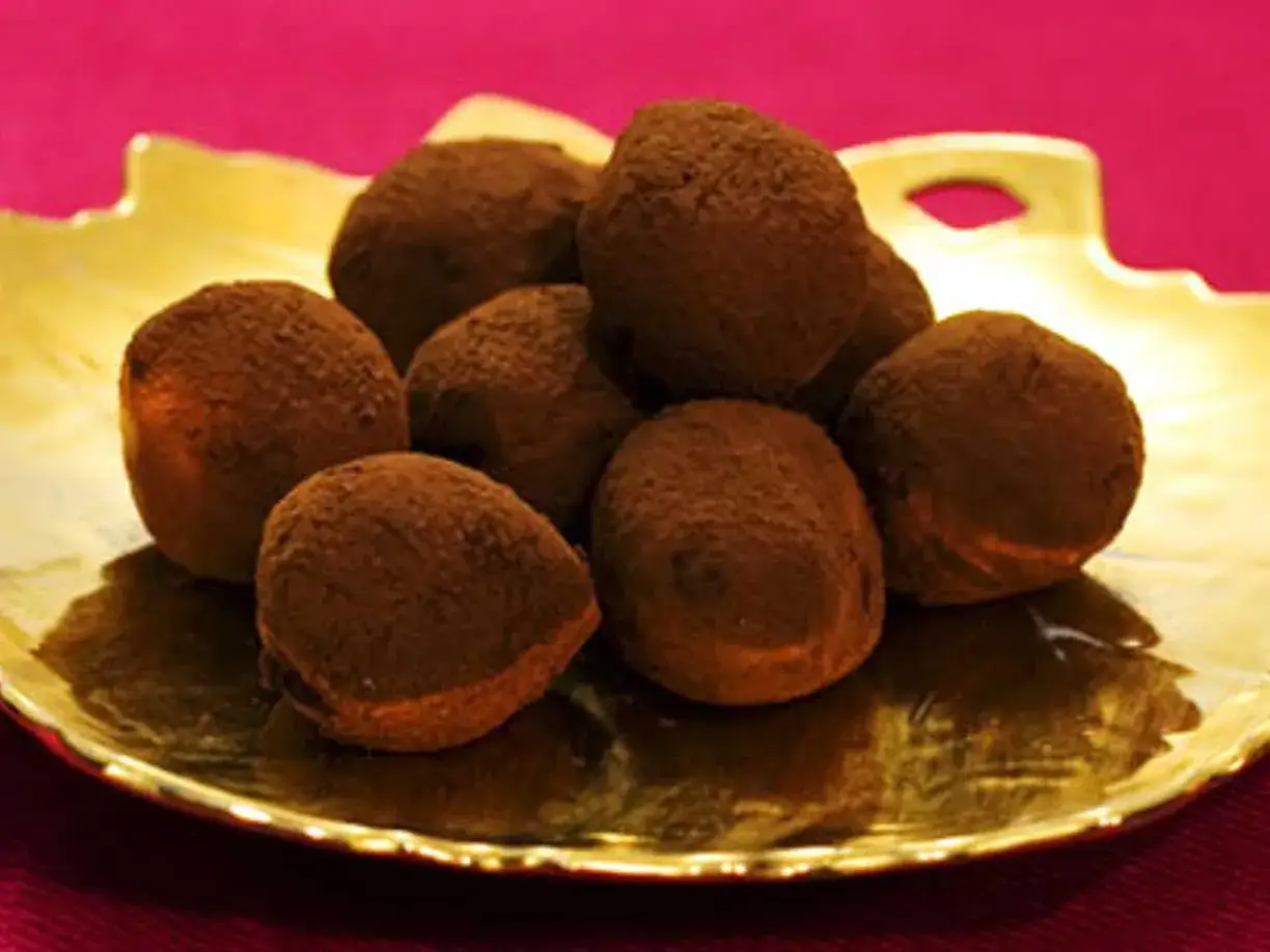 En gyllene bricka med chokladtryfflar, pudrade med kakao. Dessa läckra trufas de chocolate ser ut att smälta i munnen.