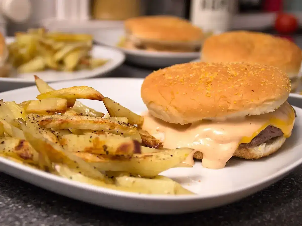 En saftig hamburguesa med smält ost och en sida av gyllene pommes frites, perfekt för en mysig kväll.