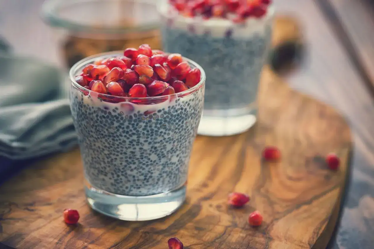 Två glas med chiafrön och gröt toppad med granatäppelkärnor. En hälsosam frukost med nyttiga semillas de chia.