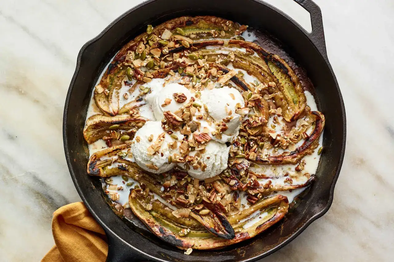 Ugnsbakade platanos i en gjutjärnspanna, toppade med vaniljglass och en krispig nötblandning. En härlig dessert i sin fulla glans.