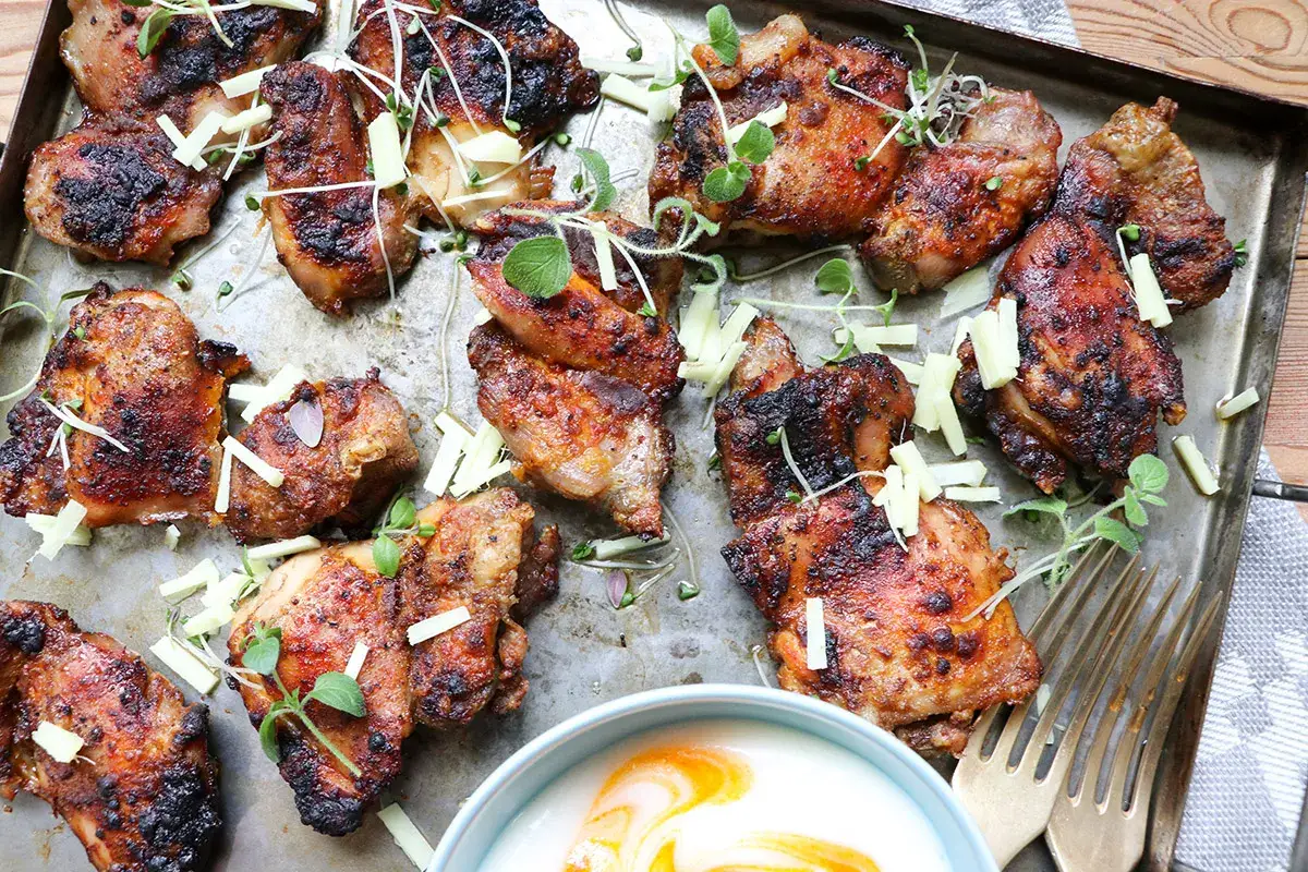 Grillad kycklingfilé, sazonar pechuga de pollo a la plancha, serverad med örter och en skål med sås.
