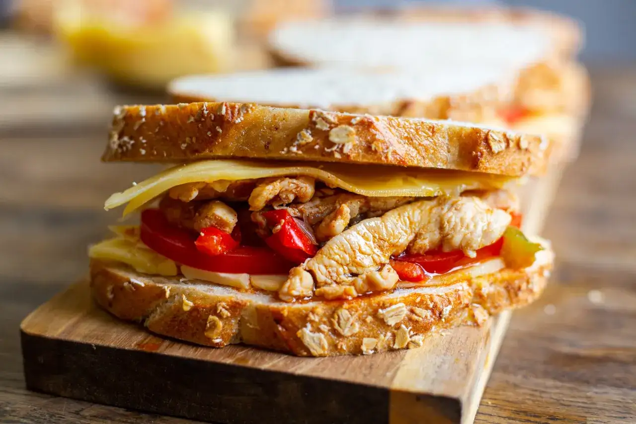 En saftig sandwich med smulad kyckling, ost och tomat på grovt bröd.