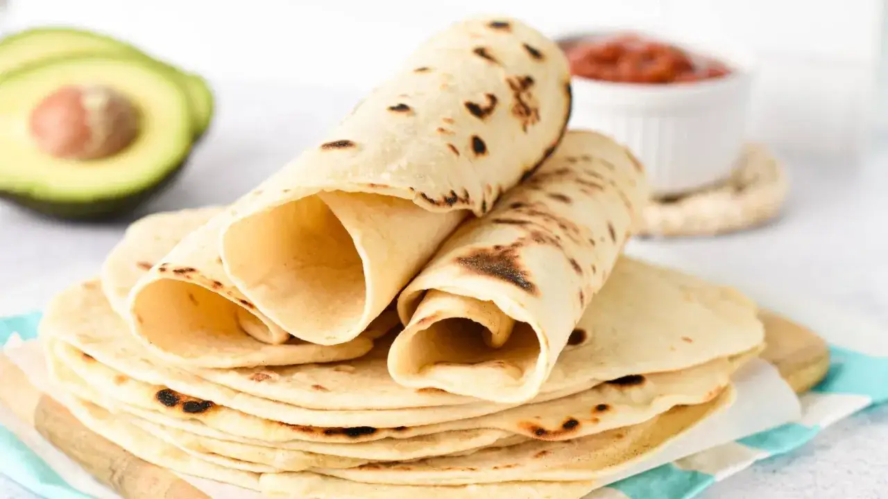 En hög med nygräddade tortillas, med en halv avokado och en skål salsa i bakgrunden. Undrar du cuantas calorias tiene una tortilla?