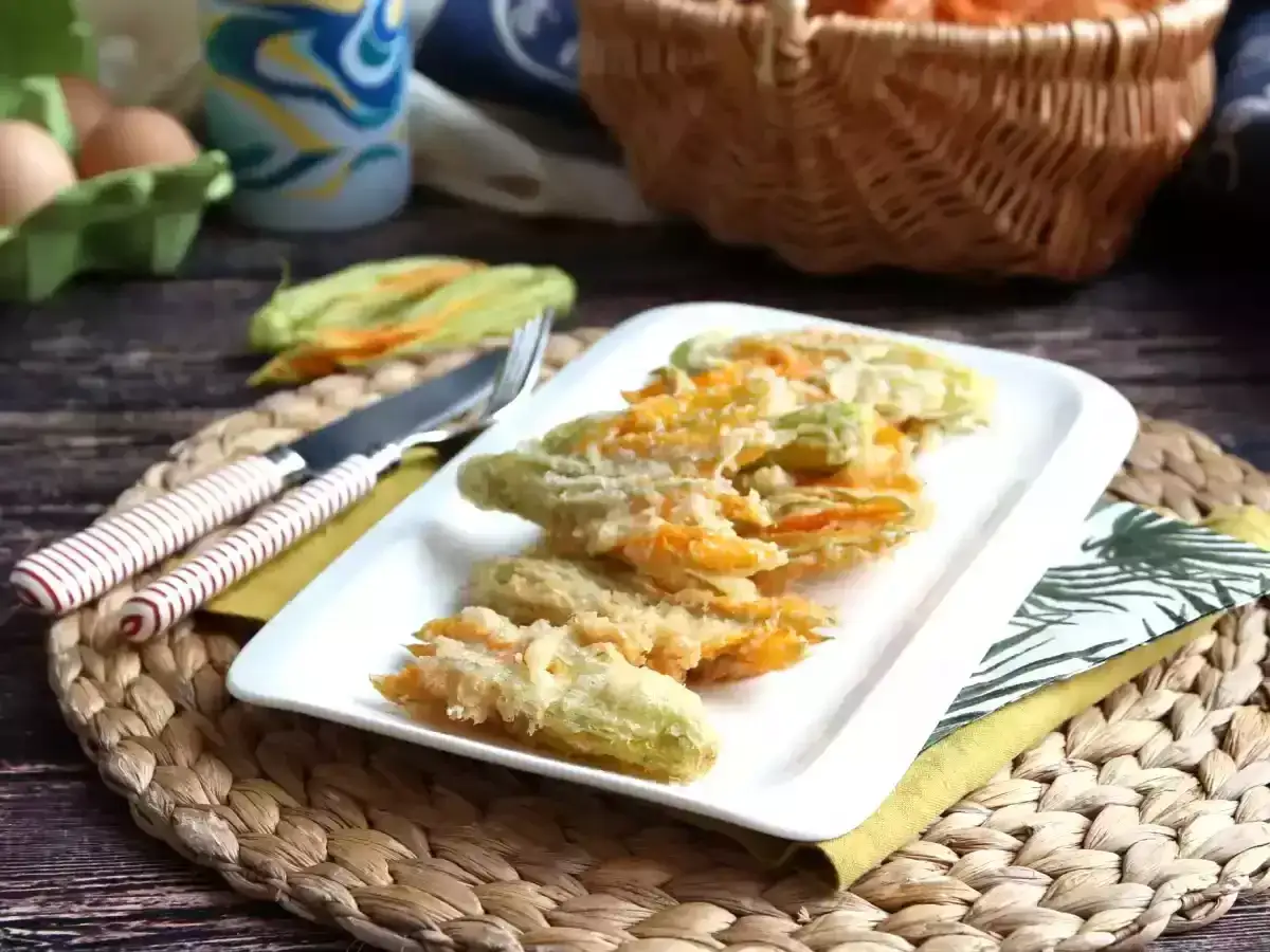 Friterade flor de calabaza p&aring; en vit tallrik, redo att avnjutas. Bredvid ligger en kniv och gaffel.