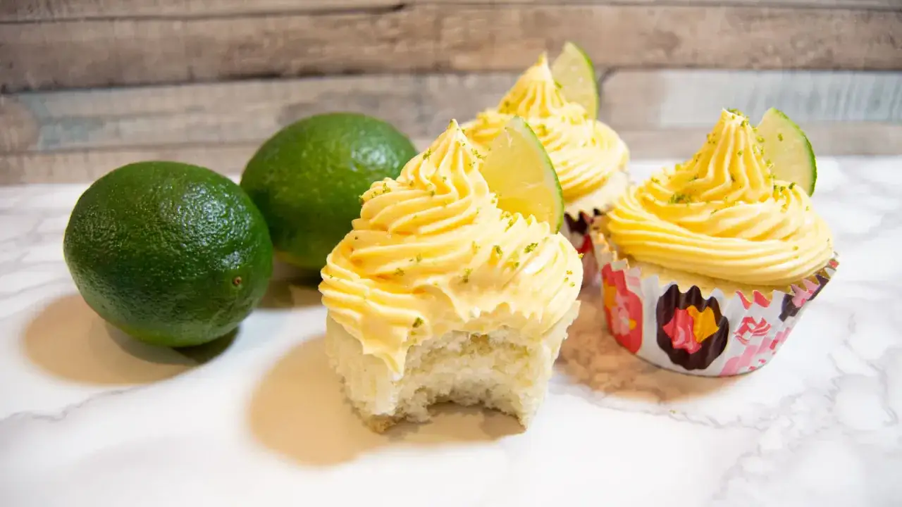 Cupcakes med limefrosting, inspirerade av cómo hacer mangoneadas. Två limefrukter ligger bredvid.