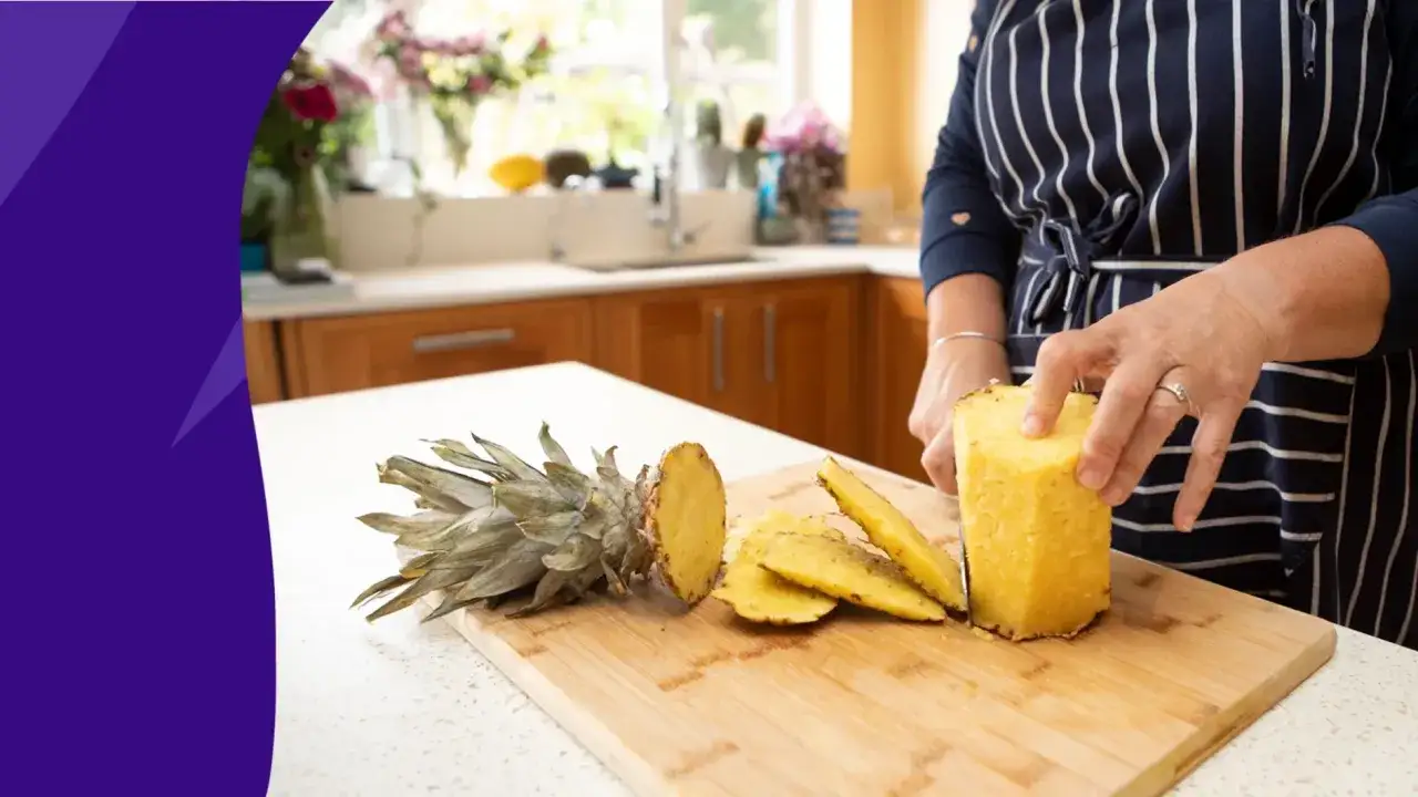 En person skär ananas på en skärbräda. Skalet kan användas för att göra te eller vinäger.