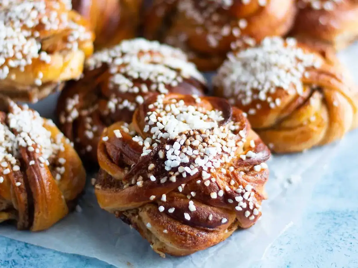 En närbild av nybakade kanelbullar, toppade med pärlsocker. Perfekt för fikat!