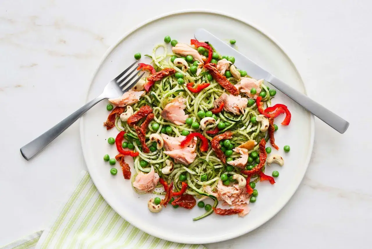 En tallrik med zucchinipasta, lax, &auml;rtor, soltorkade tomater och paprika. En h&auml;lsosam och l&auml;tt m&aring;ltid.