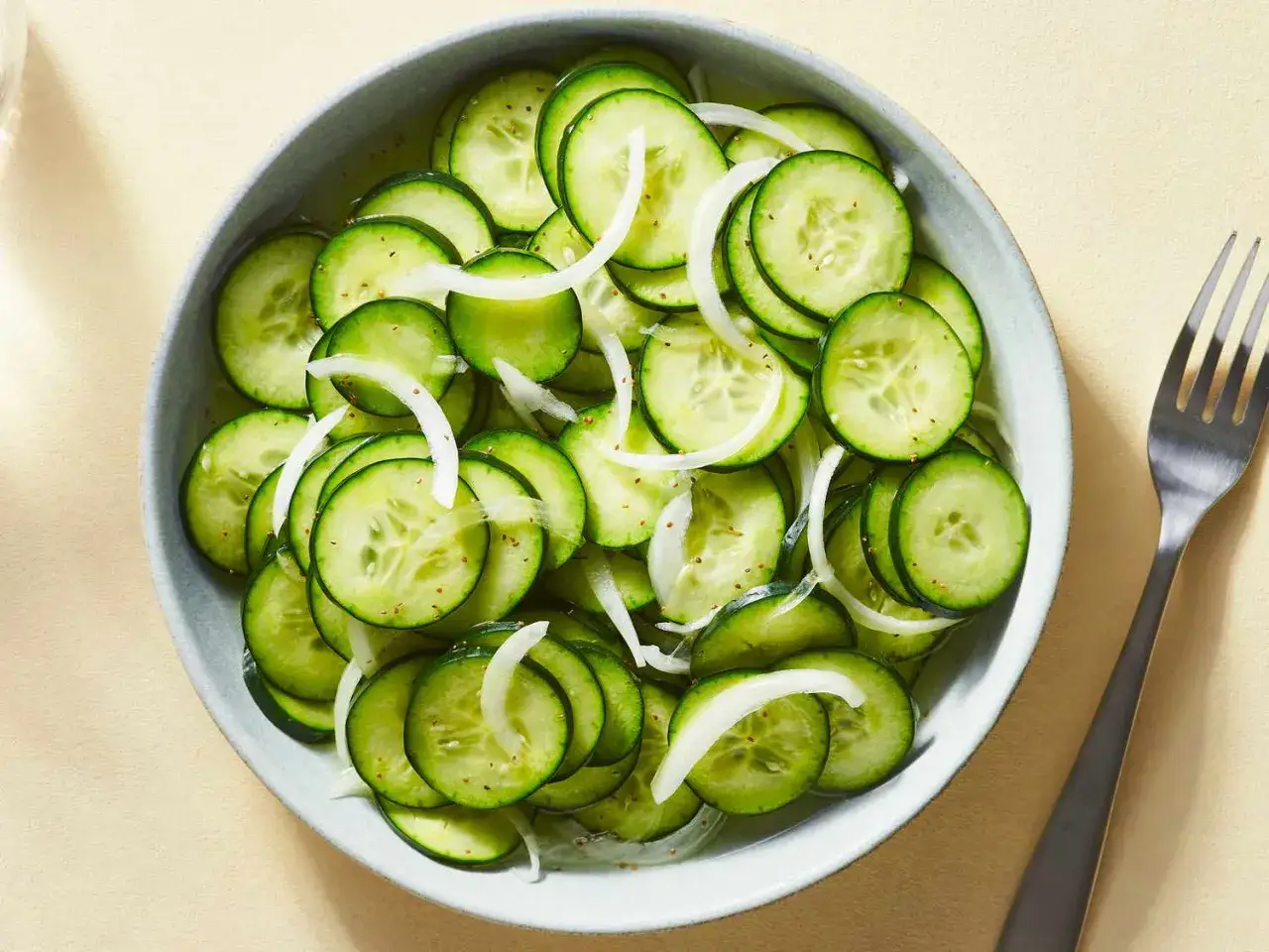 En skål med skivad gurka och lök, en fräsch sallad som får en att fundera: el pepino es fruta o verdura?