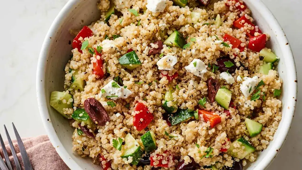 En skål med grekisk quinoasallad, perfekt för att visa para qué sirve la quinoa – som en näringsrik bas för en fräsch och mättande måltid.