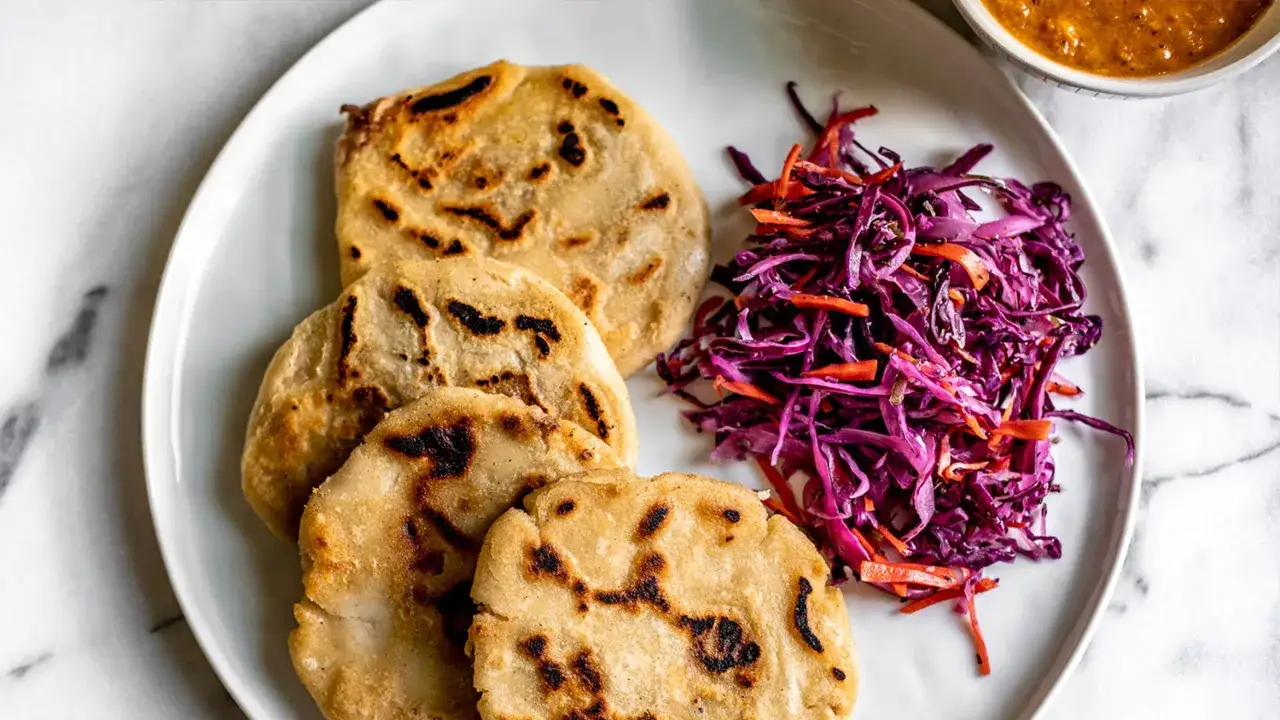 Pupusas, en del av den autentiska receta original pupusas salvadore&ntilde;as, serveras med en fr&auml;sch r&ouml;dk&aring;lssallad och en kryddig s&aring;s.