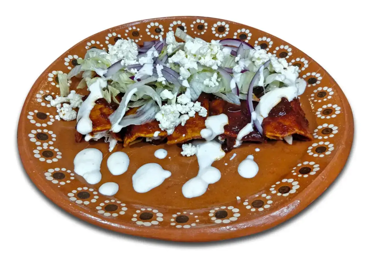 Enchiladas, en typisk guatemalansk rätt, serveras på en vackert dekorerad lertallrik med ost, sallad och lök.