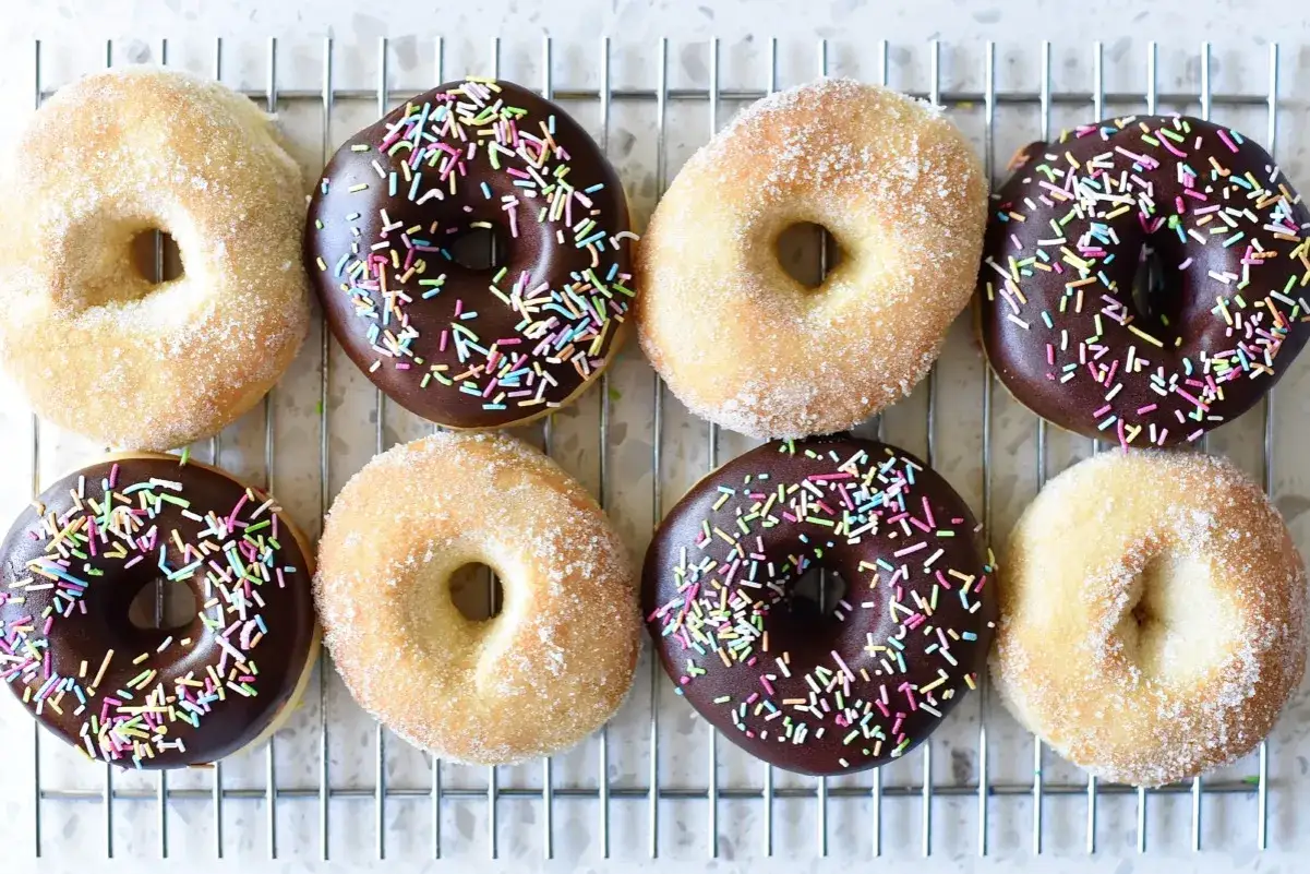 &Aring;tta donuts p&aring; ett galler, fyra med chokladglasyr och str&ouml;ssel, fyra med socker. Perfekt f&ouml;r att inspireras av nya recetas de donas.