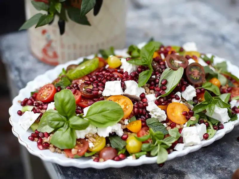 En färgstark sallad med granatäpple, tomater, fetaost och basilika. Perfekt för att visa para qué sirve la ensalada – en hälsosam och god måltid!