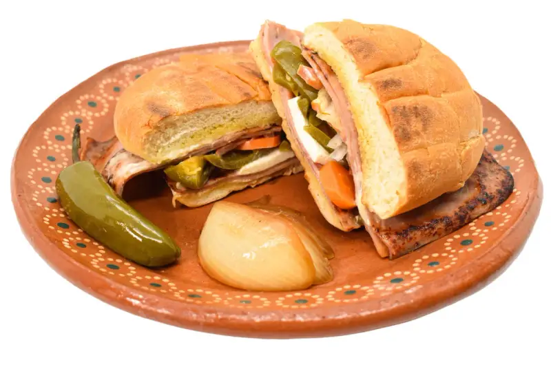 En saftig torta de jamón med jalapeños, morötter och ost på en vacker lertallrik.
