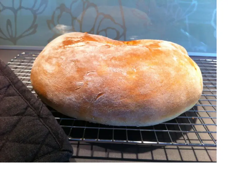 Ett nybakat, fluffigt **pan de torta** vilar på ett galler. En mörk grytlapp ligger bredvid.